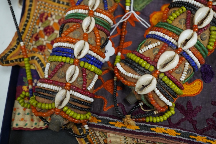 19th and 20th century textiles: An Indian mirrored and patchwork bag, a smaller embroidered bag, an ‘arrow’ shaped mirrored panel and two Omani shell and beaded ‘anchor’ shaped hangings, ‘arrow’ hanging 45cm long and two